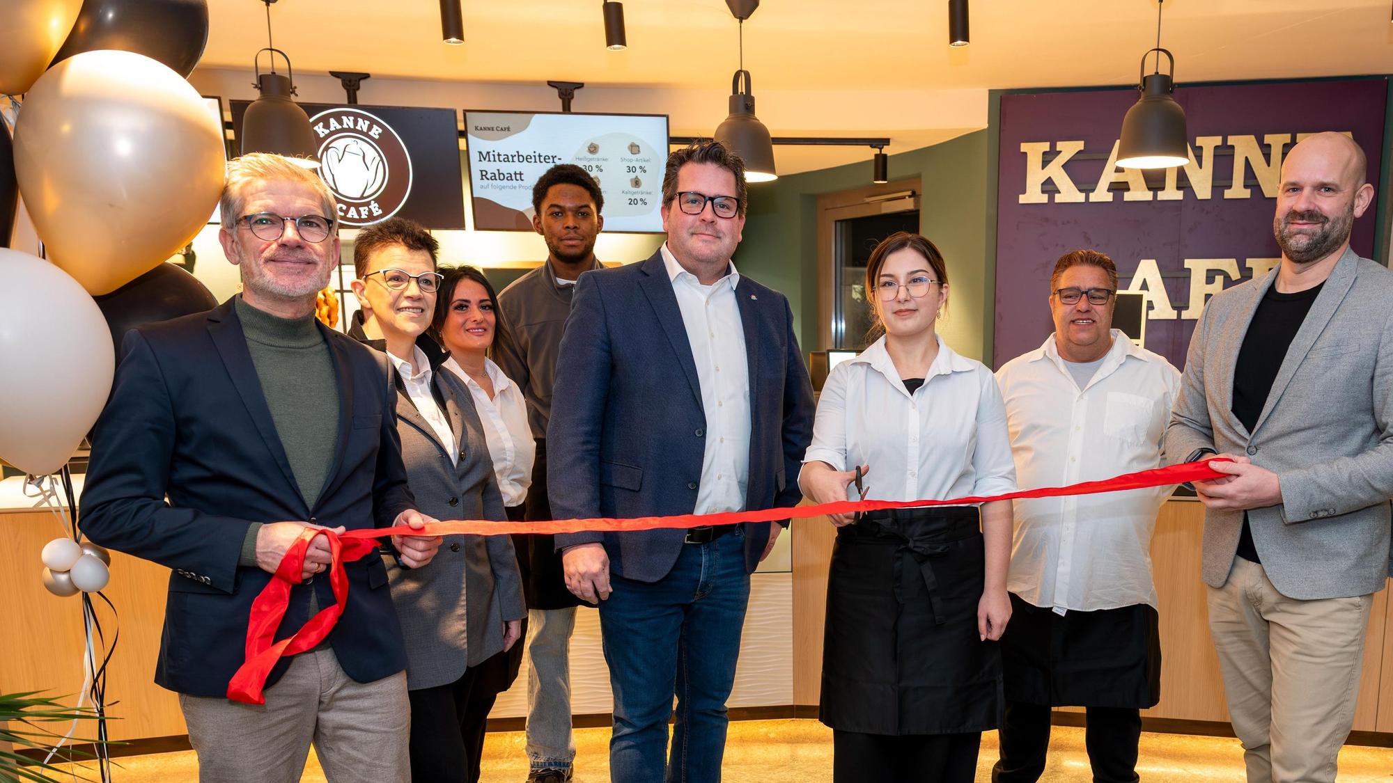 Sebastian Haeger (Geschäftsführer Gesundheitscampus Quirlsberg), der Area Manager von Kanne Café Andreas Brachem und das Team des Cafés schneiden zur Eröffnung im EVK ein rotes Band durch.