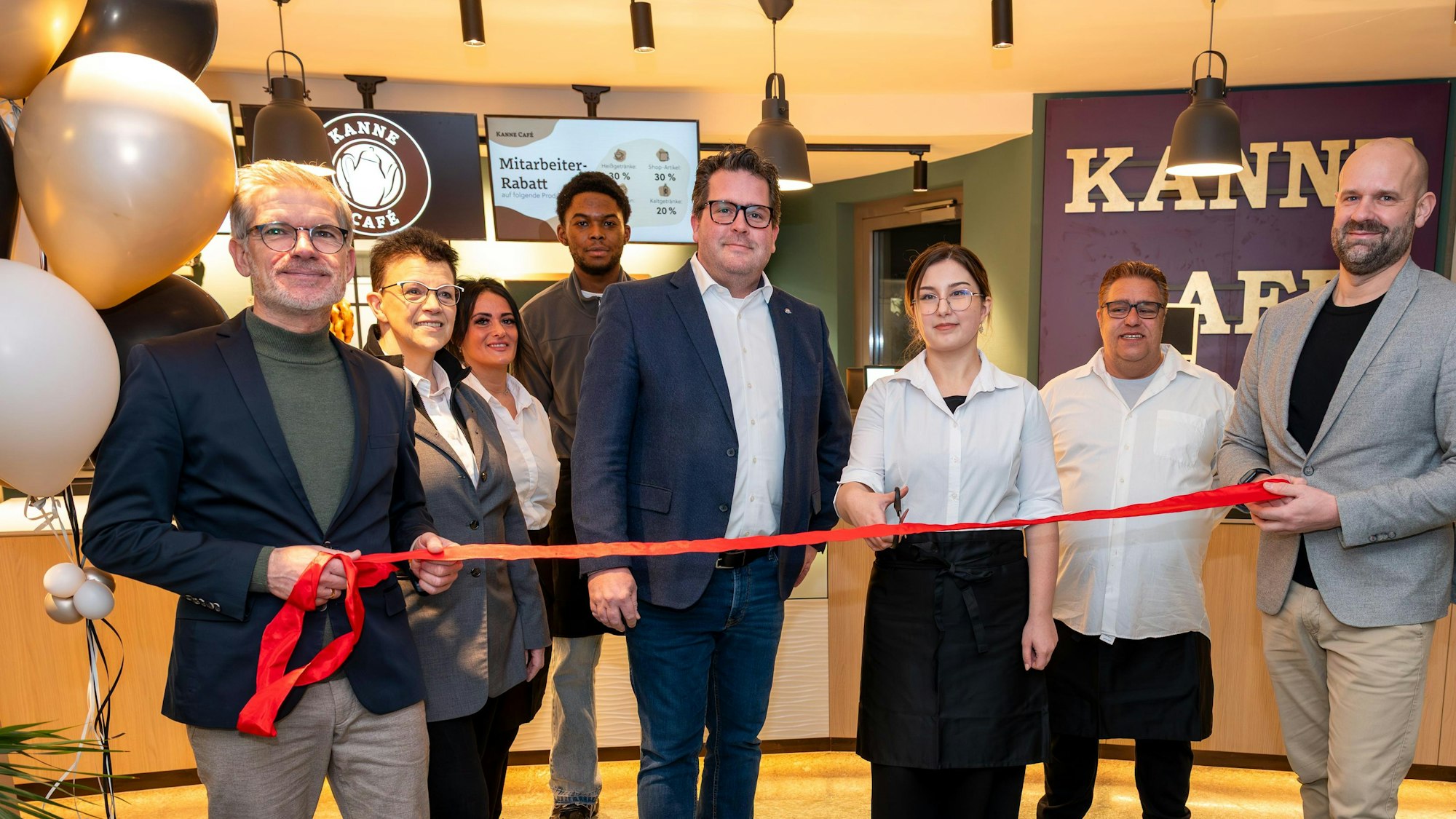 Sebastian Haeger (Geschäftsführer Gesundheitscampus Quirlsberg), der Area Manager von Kanne Café Andreas Brachem und das Team des Cafés schneiden zur Eröffnung im EVK ein rotes Band durch.