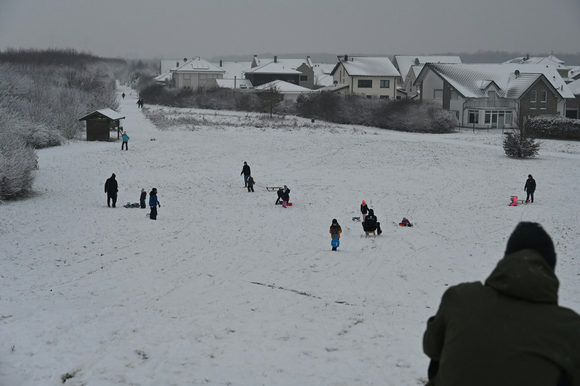 Das Bild zeigt Kinder mit Schlitten an einem Rodelhang
