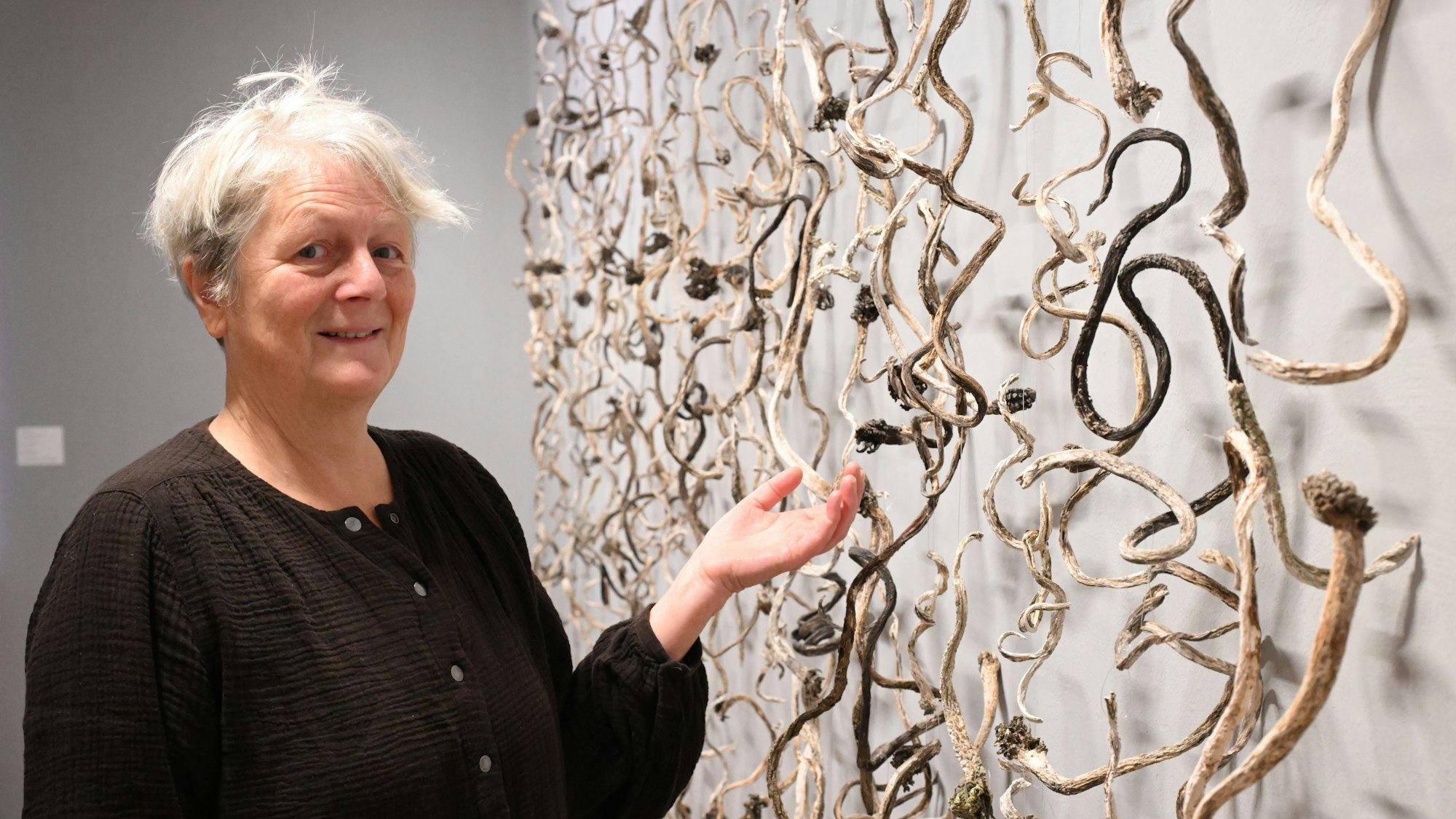 Veronika Moos steht neben einem Werk aus getrockneten Algen.