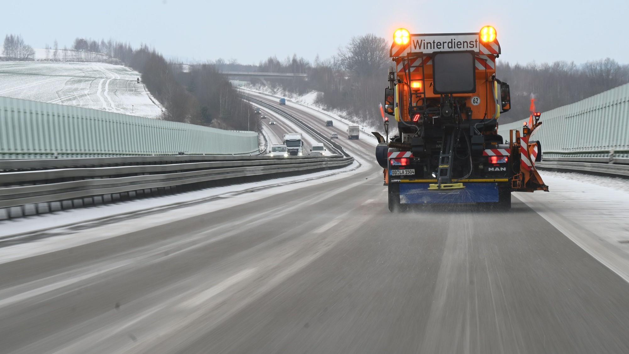 Ein Fahrzeug des Winterdienstes streut die Autobahn.
