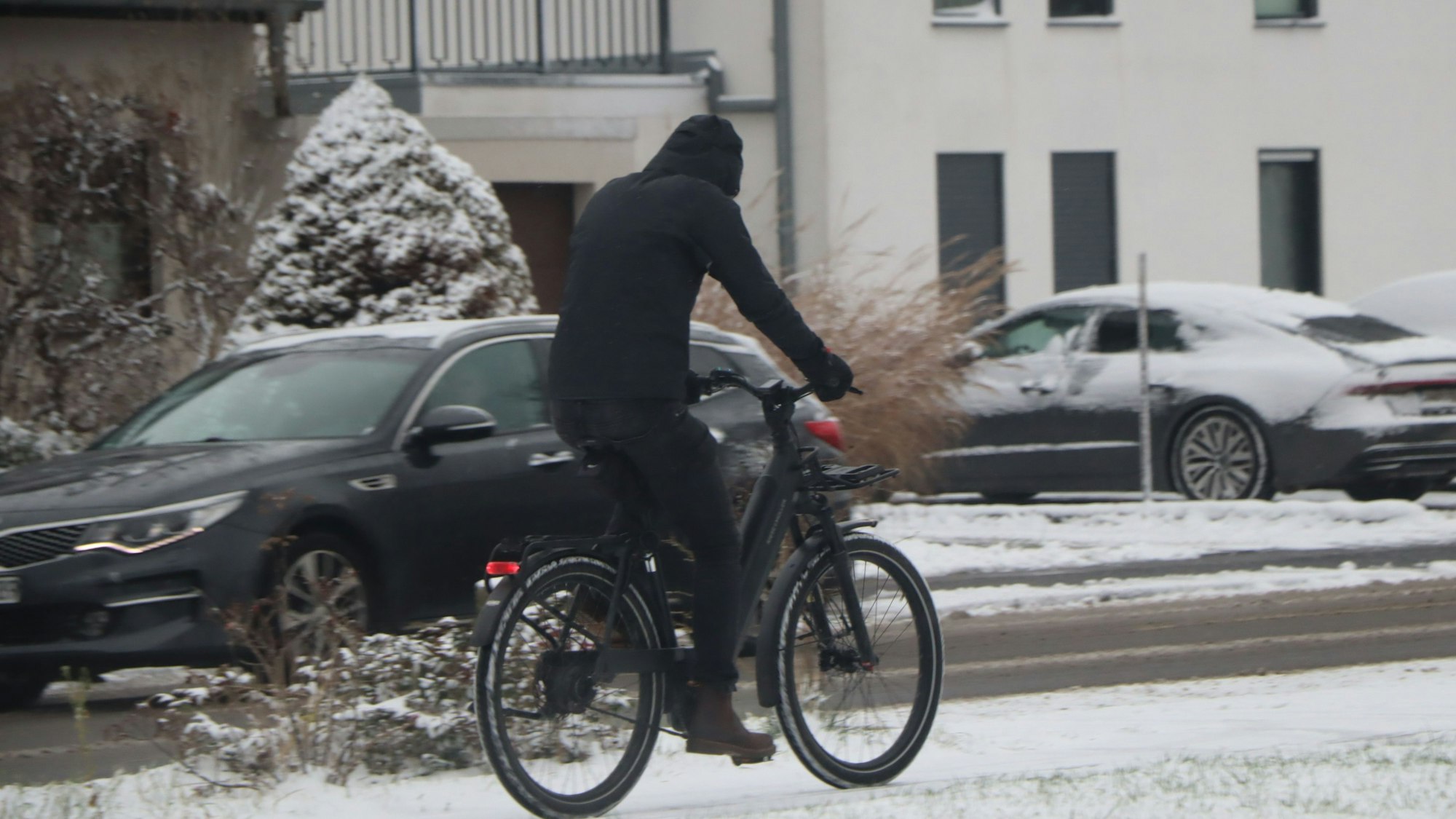 Das Bild zeigt einen Fahrradfahrer auf einem schneebedeckten Fahrradweg.