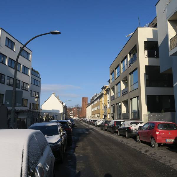 An einer Anwohnerstraße parken an beiden Fahrbahnrändern Autos.