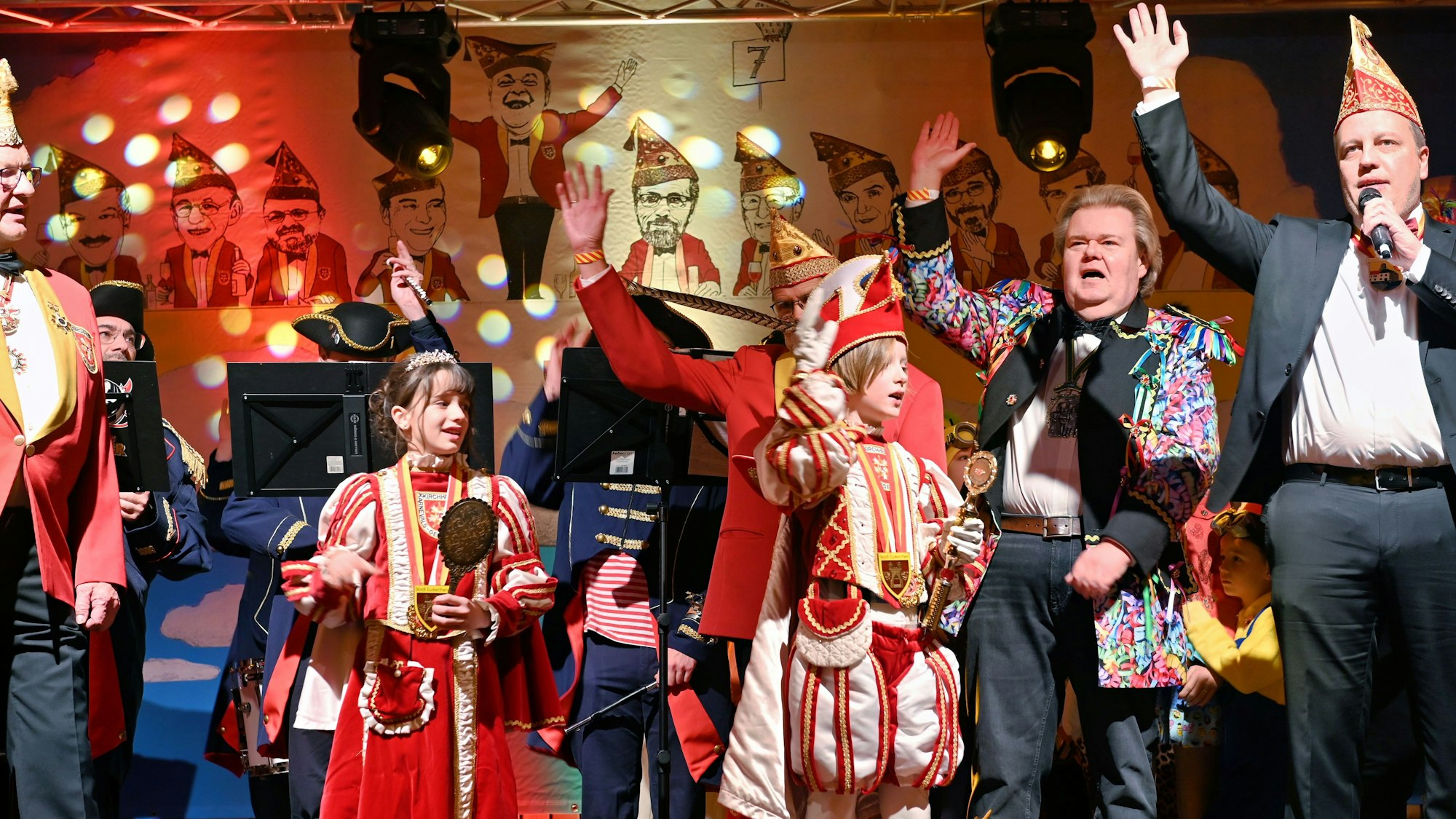 Das Kinderprinzenpaar steht in Kostümen mit einigen Erwachsenen auf der Bühne und feiert.