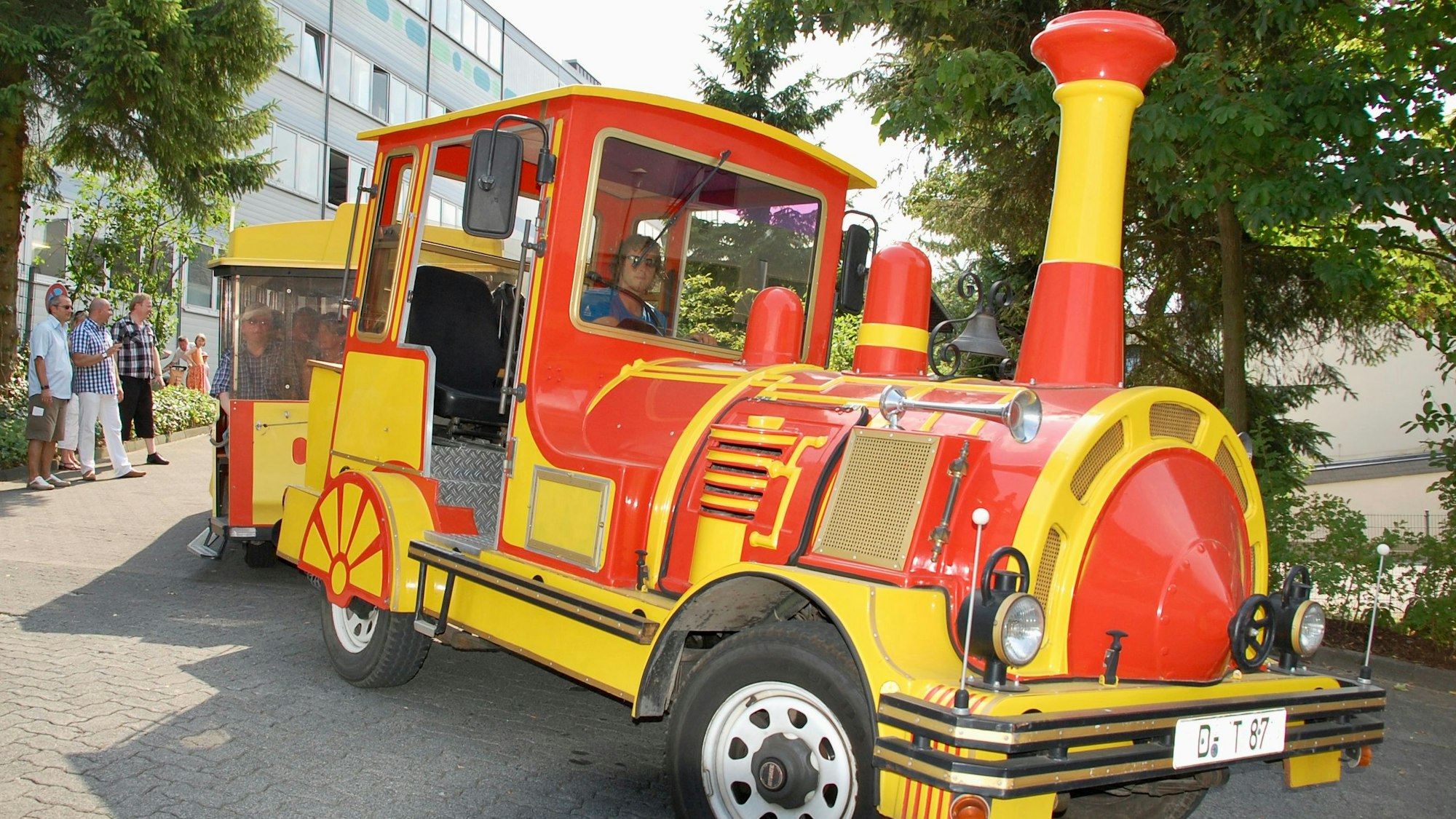 Eine gelb-rote Bimmelbahn fährt über eine Straße.