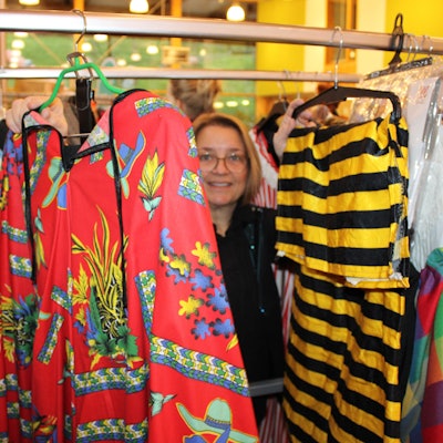 Eine Frau schaut durch auf einer Kleiderstange aufgereihte Kostüme.