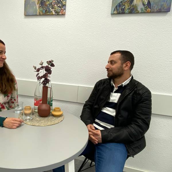 Die Kim-Case-Managerin sitzt im Gespräch mit ihrem Klienten an einem runden Tisch.