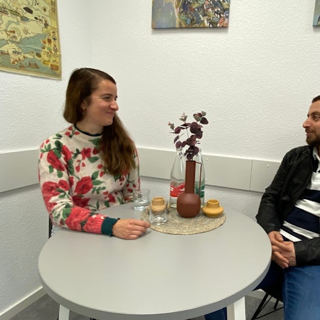 Die Kim-Case-Managerin sitzt im Gespräch mit ihrem Klienten an einem runden Tisch.