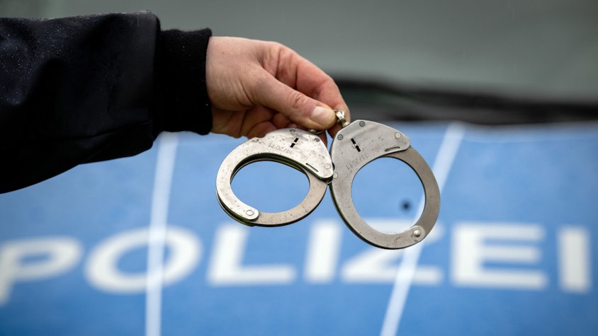 Ein Polizist hält ein Paar Handschellen