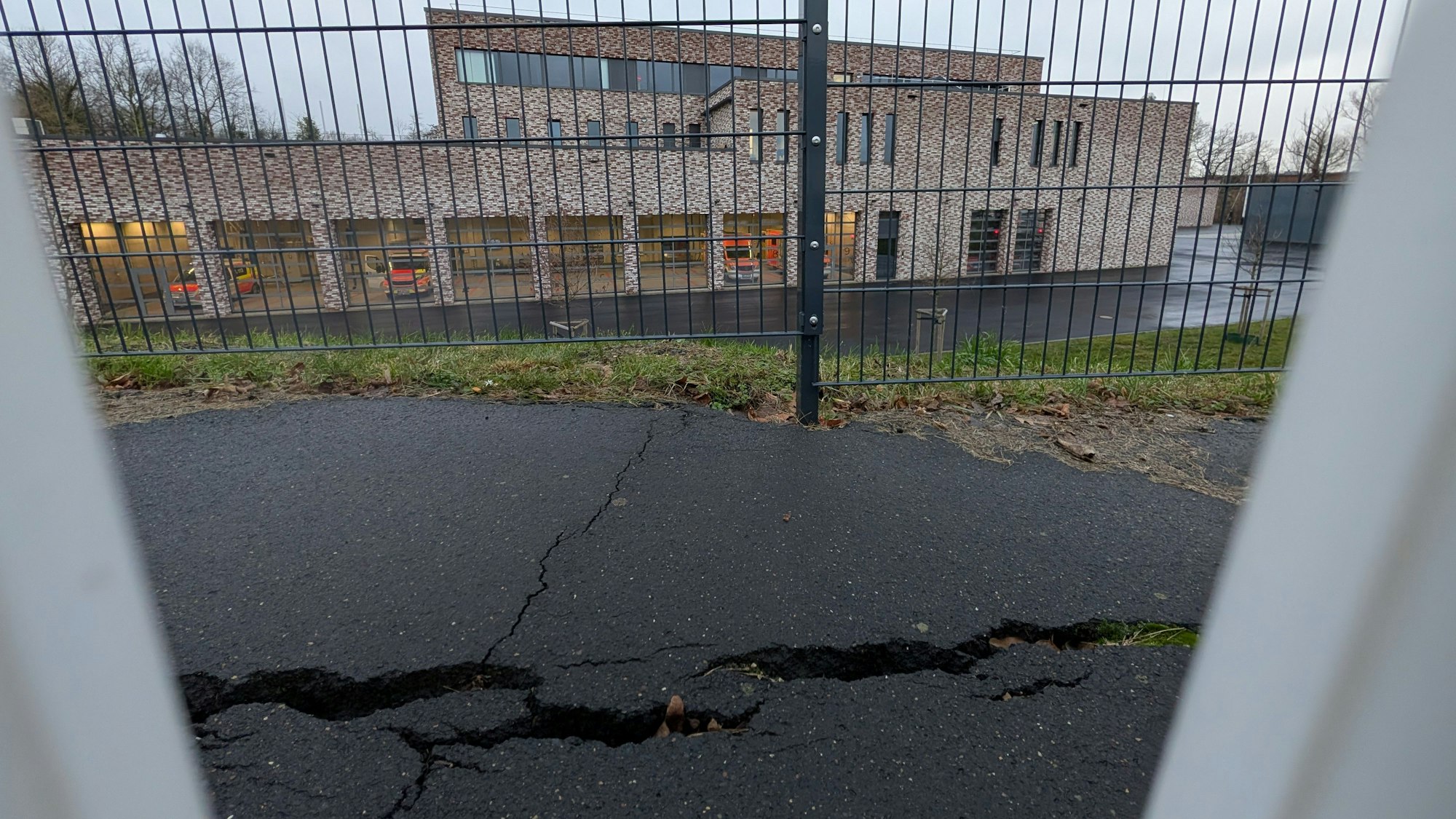 Das Foto zeigt den Riss im Asphalt auf dem Gehweg vor der Feuerwehr, im Hintegrund die Feuerwache.