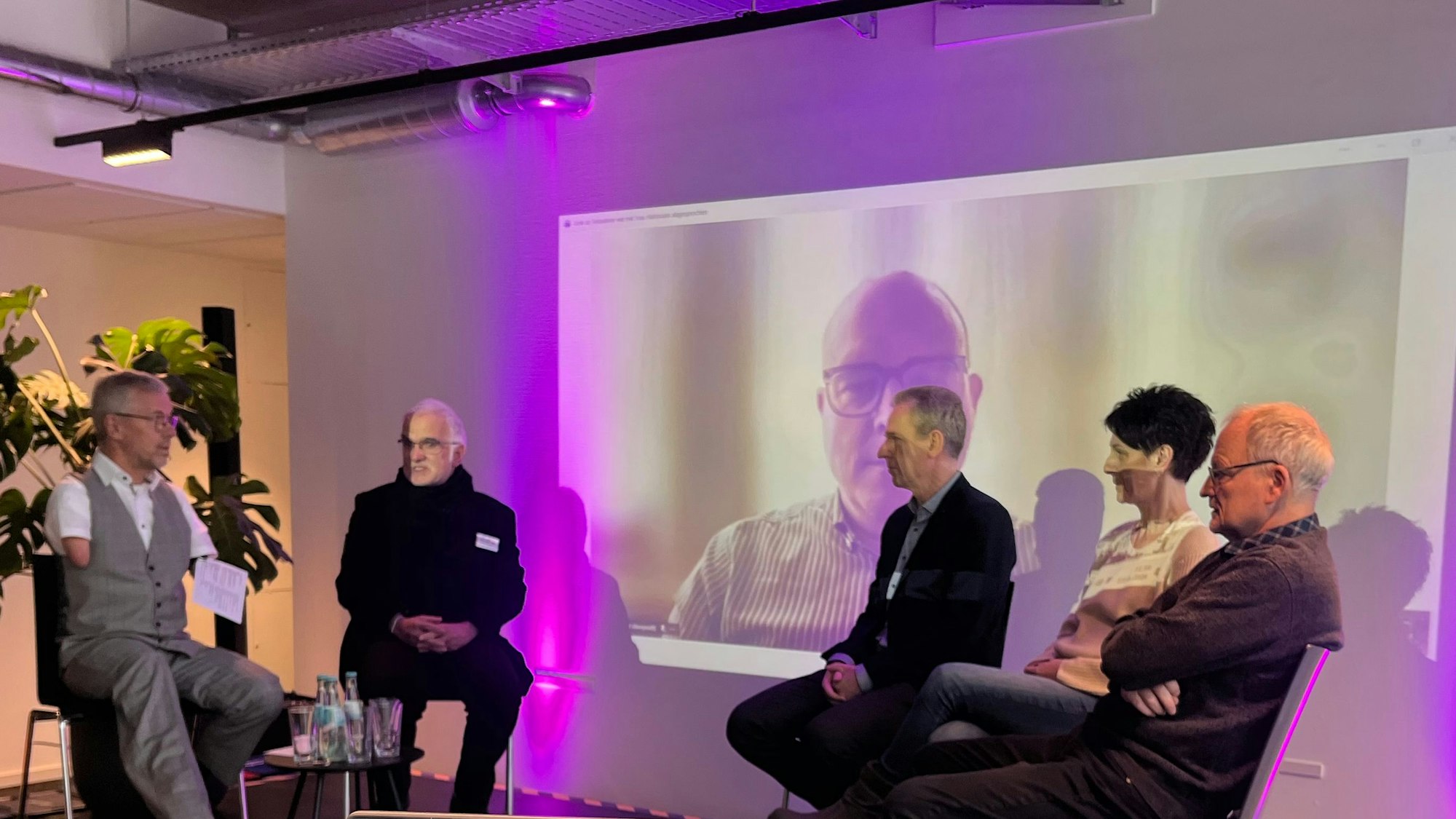 Diskussionsrunde auf einer Bühne: Rainer Schmidt (l.) sprach mit (v.l.) Wilfried Fenner von der Fachberatungsstelle, Martin Kositzka (Bundesarbeitsgemeinschaft Wohnungslosenhilfe, auf der Leinwand im Hintergrund), dem Mediziner Bodo Kunkelbach, Jeanette Rath als ehemalige Betroffene und Andreas Zimmermann (LVR).