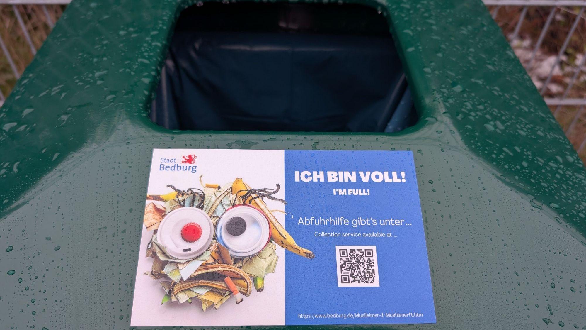 Zu sehen ist ein Aufkleber auf einem öffentlichen Mülleimer.