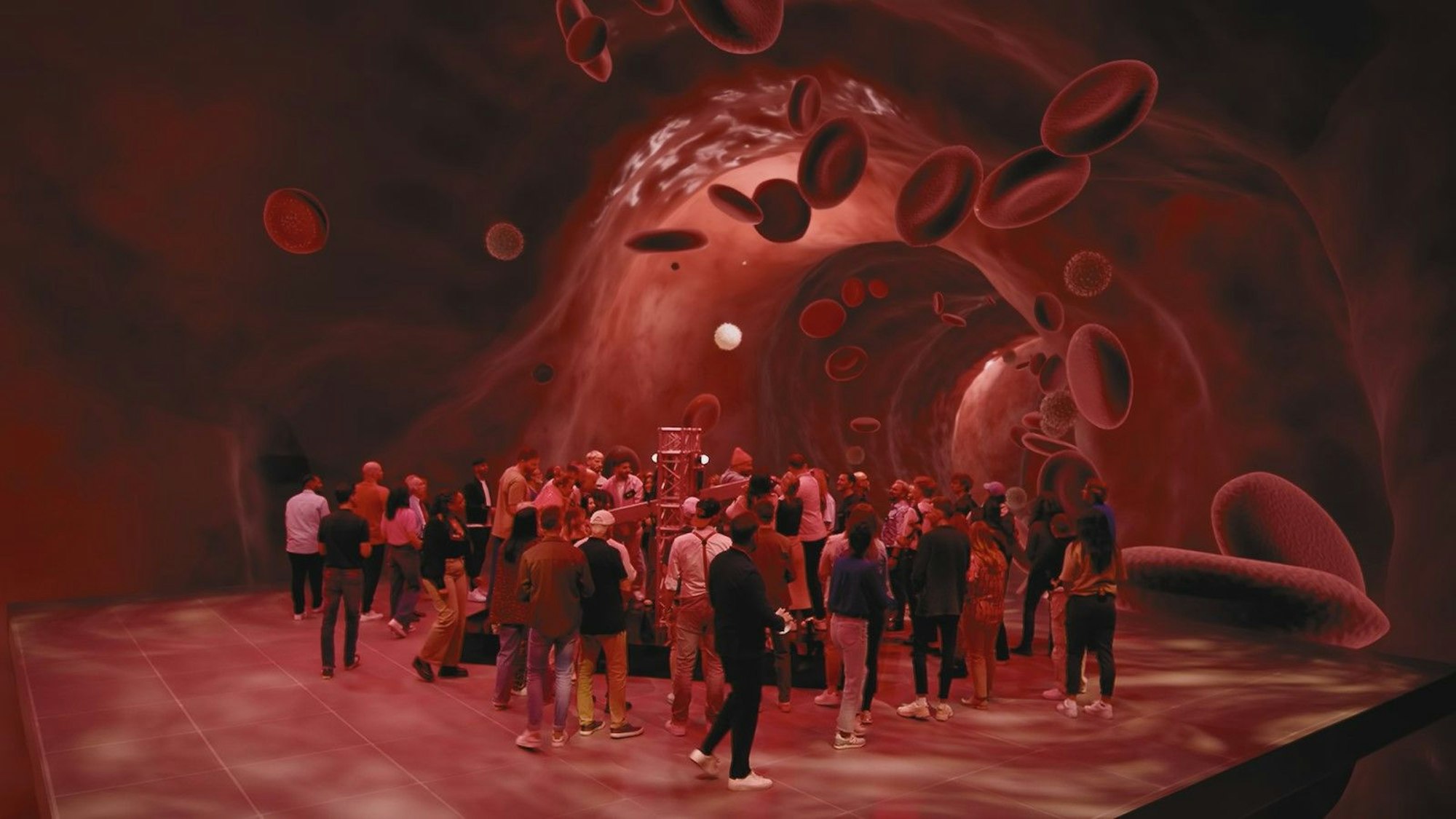 Menschen stehen in einem virtuellen Raum, der aussieht wie die menschliche Blutbahn.