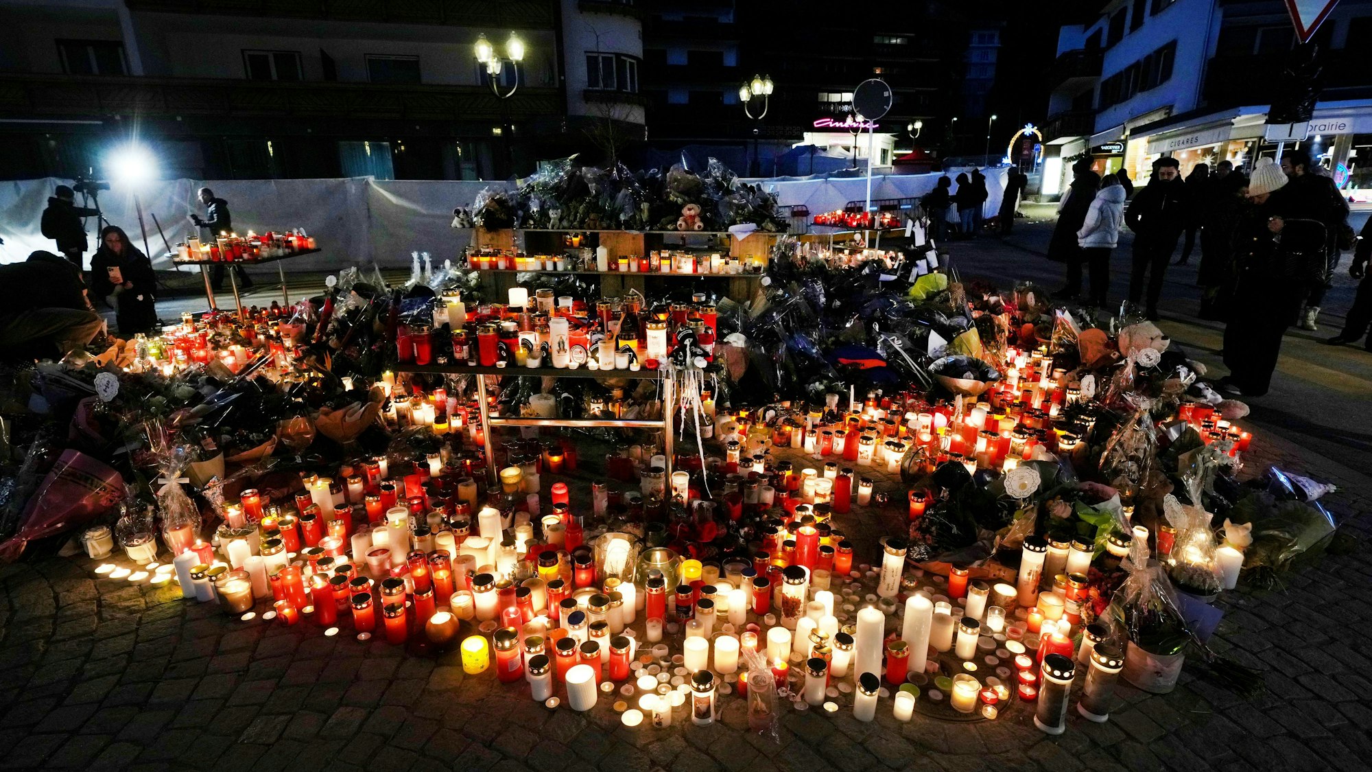 Crans Montana: Menschen zünden Kerzen an und legen Blumen vor der versiegelten Bar Le Constellation in Crans-Montana.