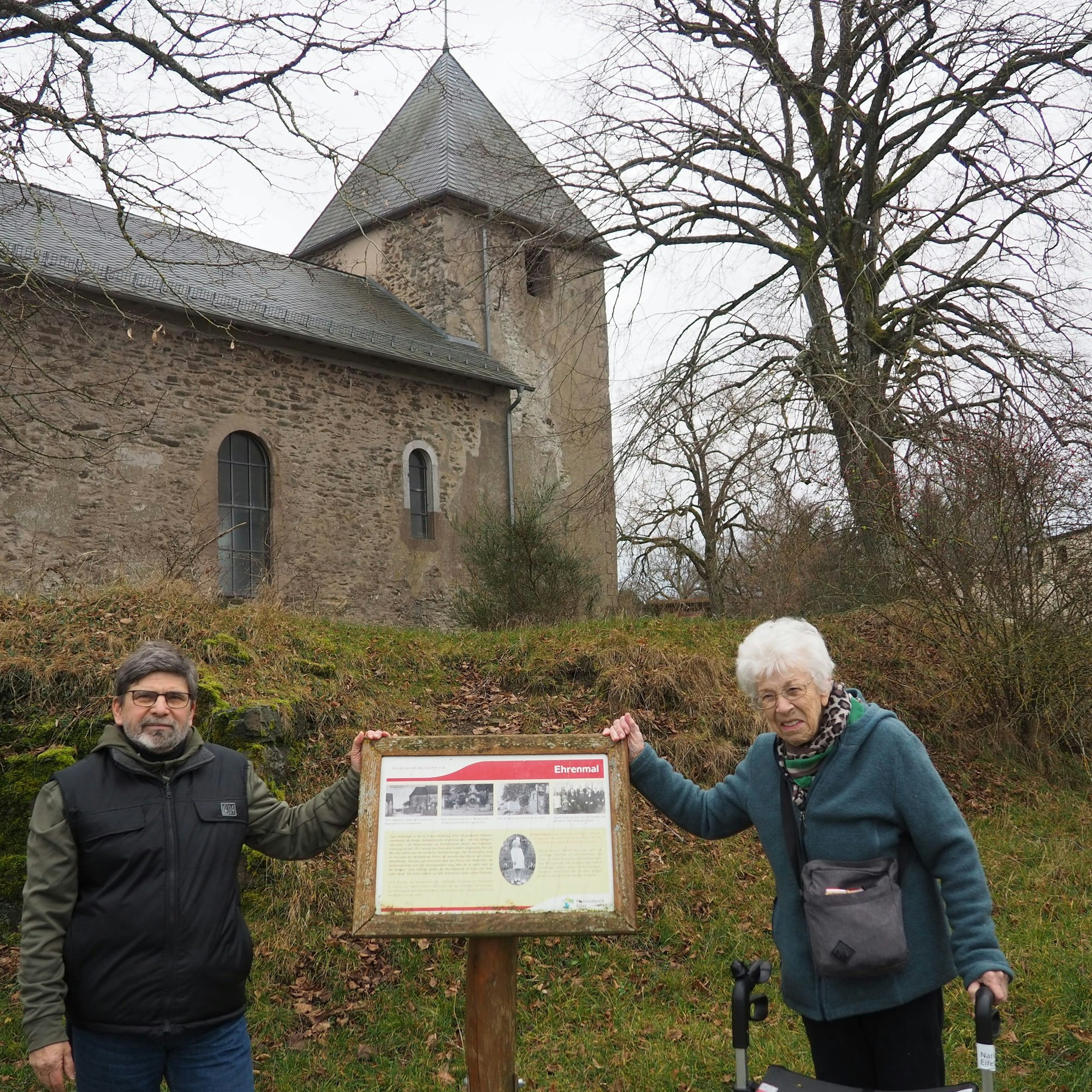 Die beiden Genannten an der Gedenktafel. Im Hintergrund ist die Kirche St. Rochus zu sehen.