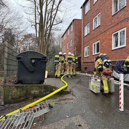Auf dem Bild sind Feuerwehrleute vor einem Backsteingebäude zu sehen.