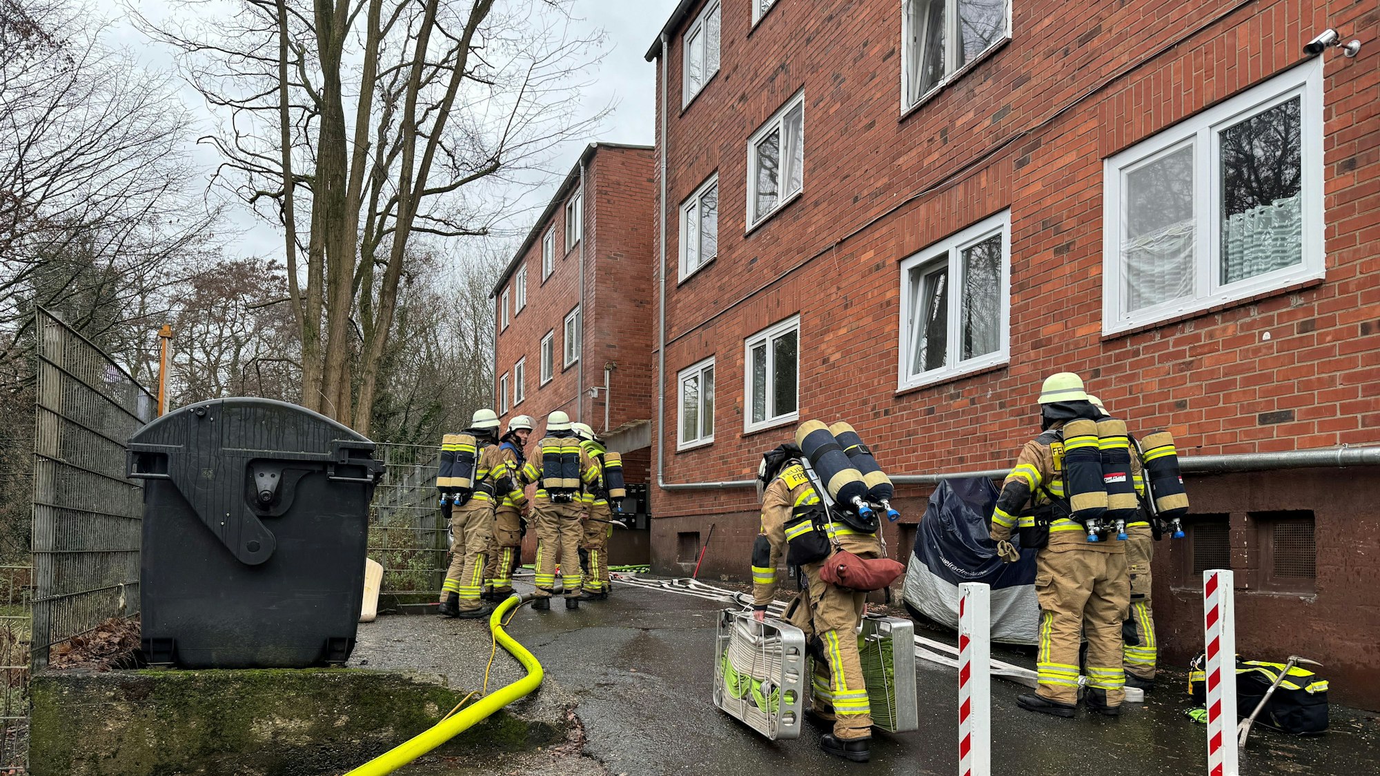 Auf dem Bild sind Feuerwehrleute vor einem Backsteingebäude zu sehen.