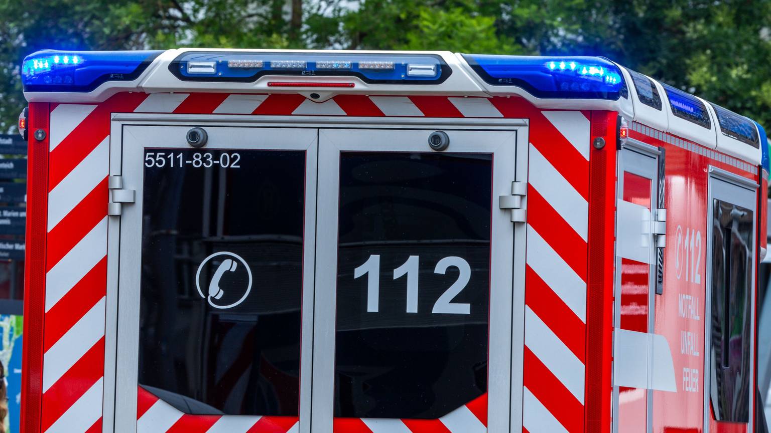 Ein Rettungsfahrzeug ist mit Blaulicht auf einer Straße in der Innenstadt unterwegs.