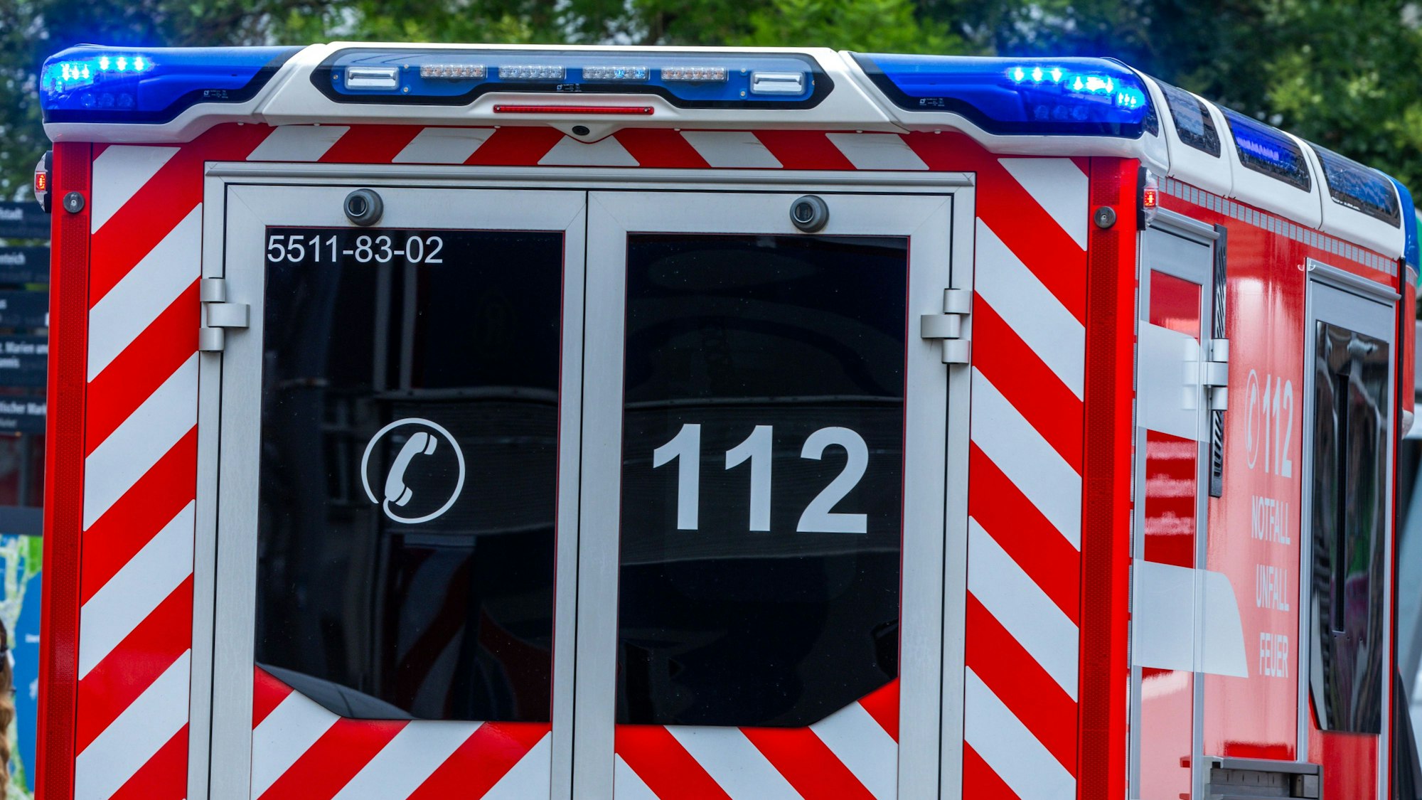 Ein Rettungsfahrzeug ist mit Blaulicht auf einer Straße in der Innenstadt unterwegs.