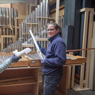 Zwei Handwerkerinnen halten Orgelpfeifen in den Händen.