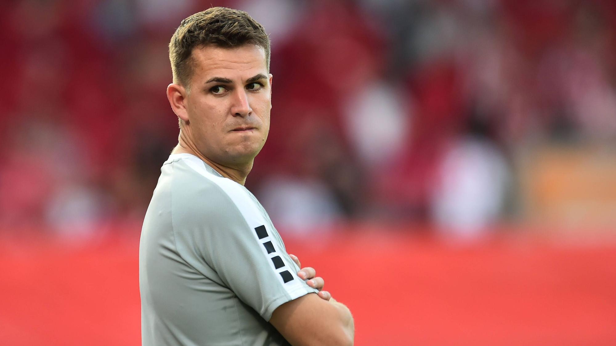 Das Foto zeigt einen Fußballtrainer mit verschränkten Armen, der über seine rechte Schulter schaut-.