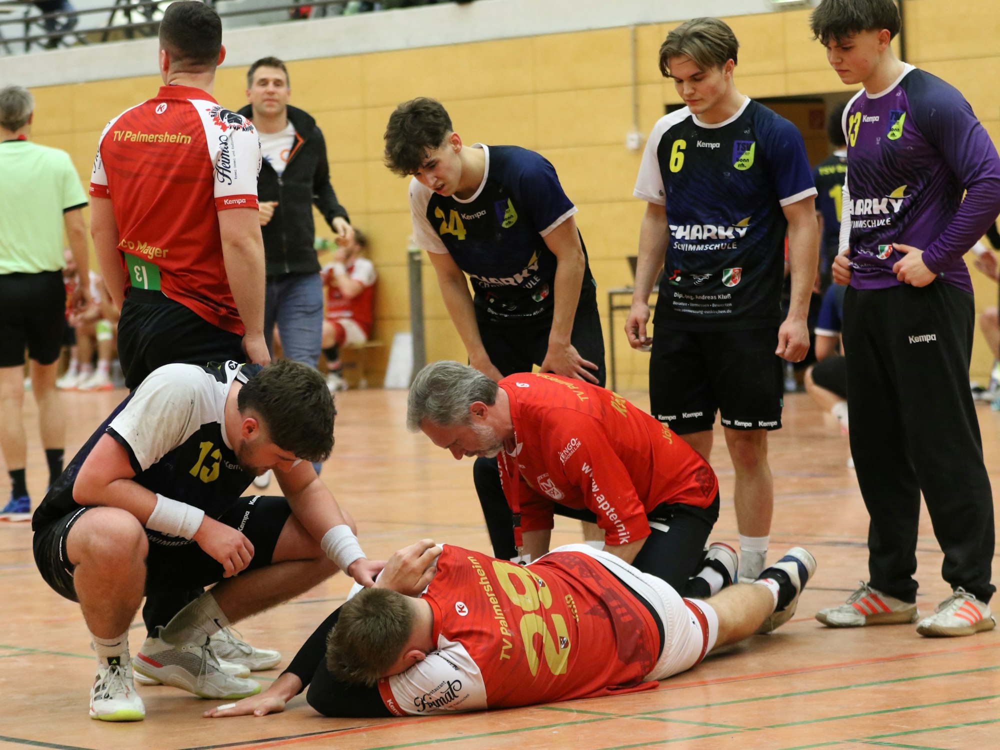 Robin Voiß liegt auf dem Boden, das Gesicht im Arm vergraben. Ein Betreuer kümmert sich um ihn. Ein gegnerische Spieler spricht ihm Trost zu.