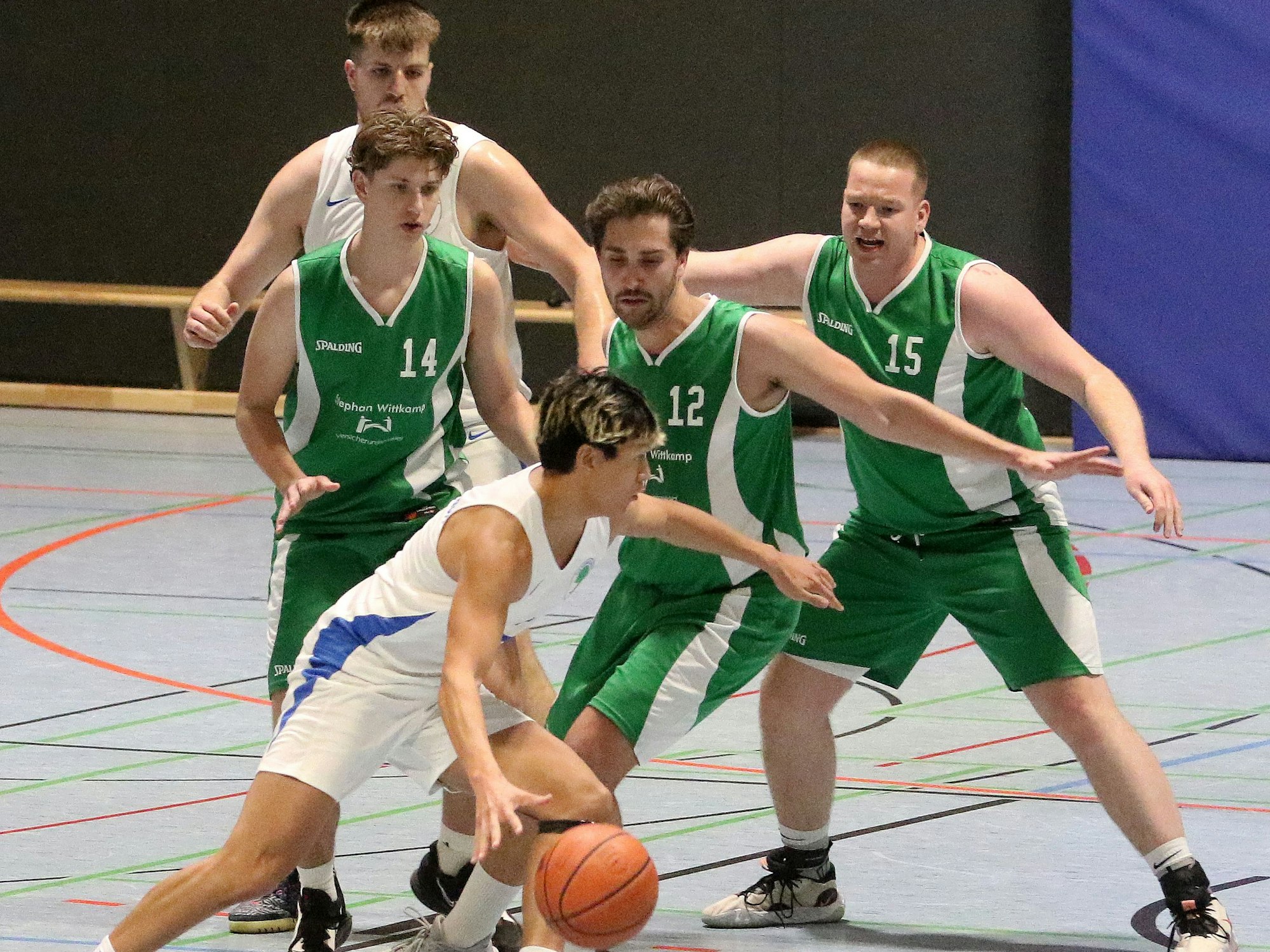 Der Königsdorfer Basketballer (in Weiß) nimmt es mit drei Gegenspielern der TS Frechen auf.