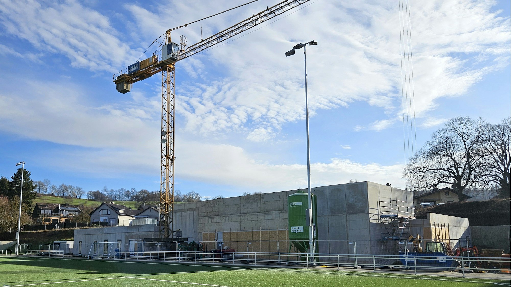 Vor dem Rohbau steht ein großer Baukran.
