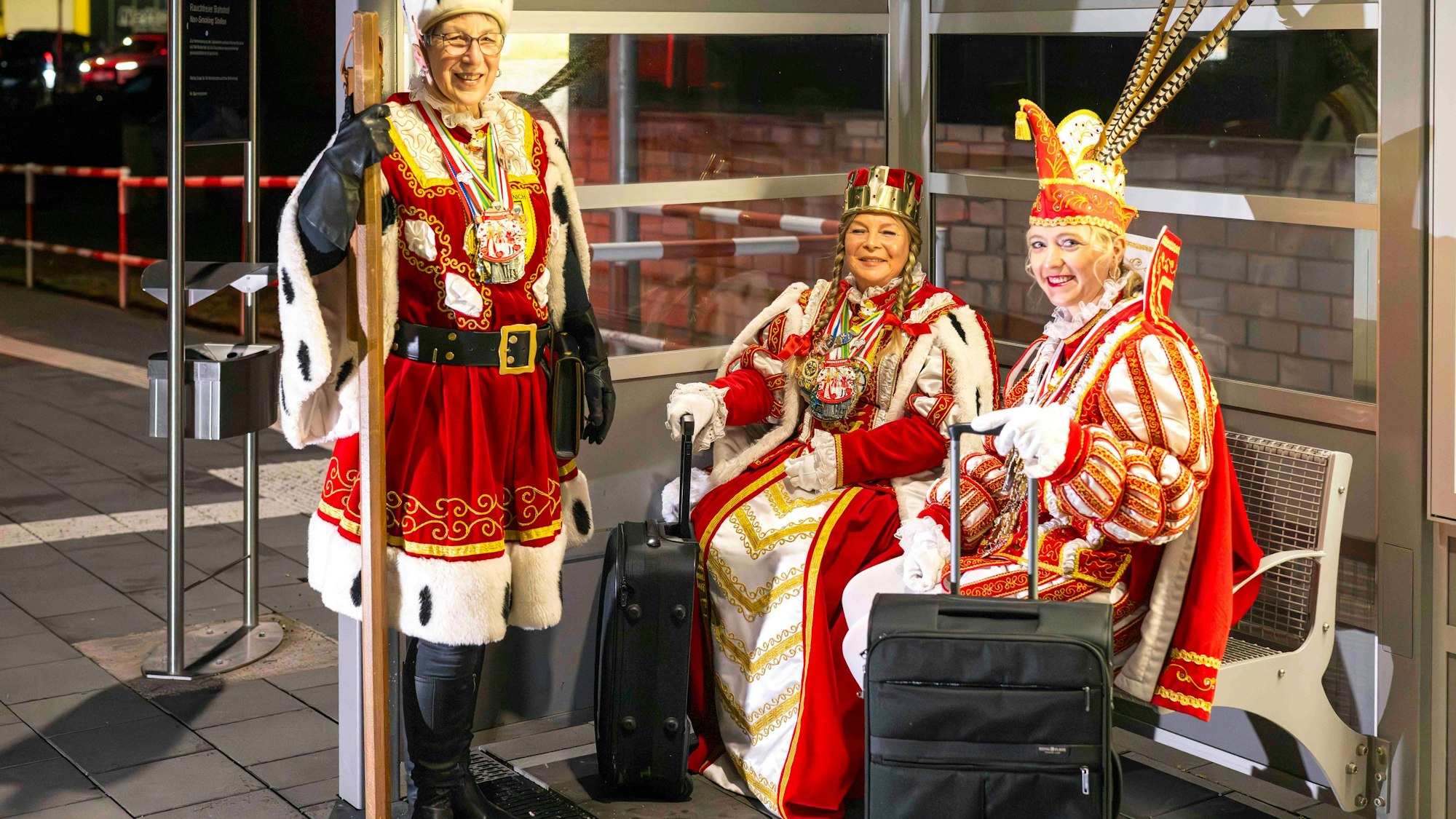 Das Bild zeigt die drei Tollitäten am Bahnhof in Arloff. Sie warten auf den Zug zum Flughafen.