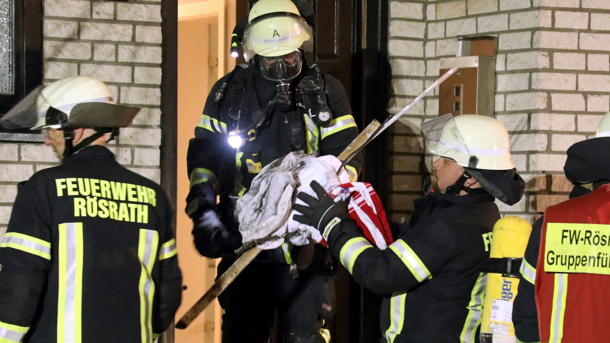 Ein Feuerwehrmann mit Atemschutz übergibt ein Bündel Müll einem anderen.