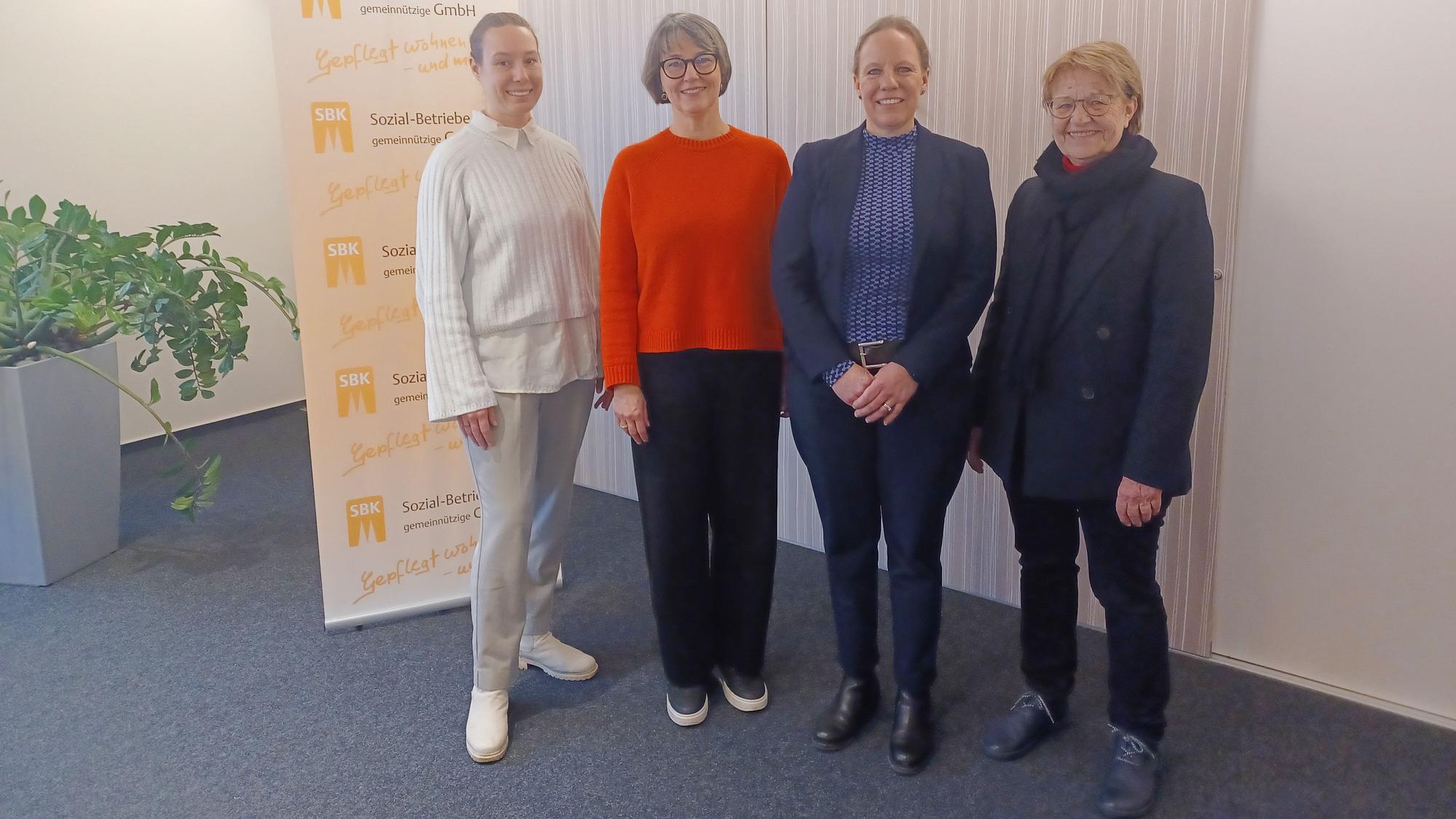 Vier Frauen stehen neben einem Banner