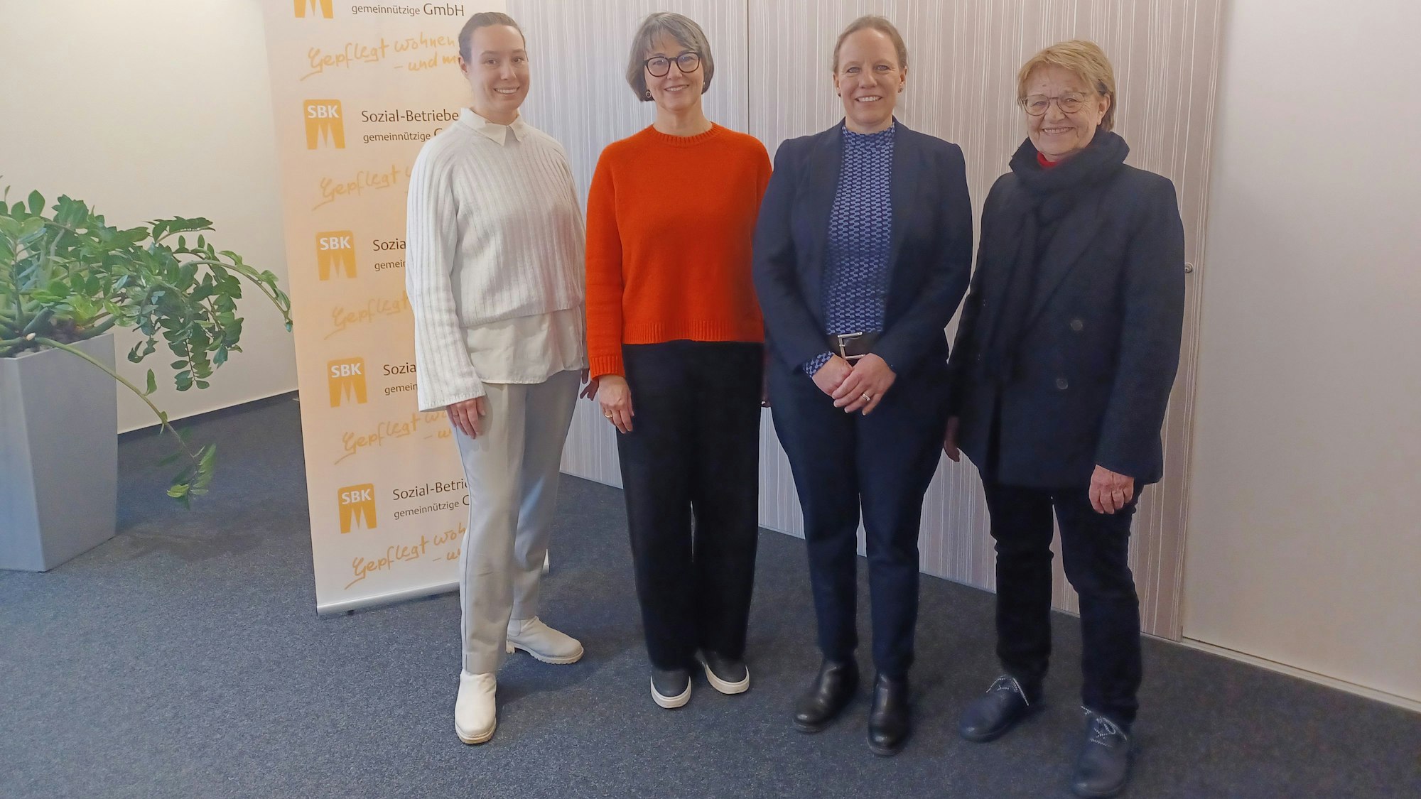 Vier Frauen stehen neben einem Banner