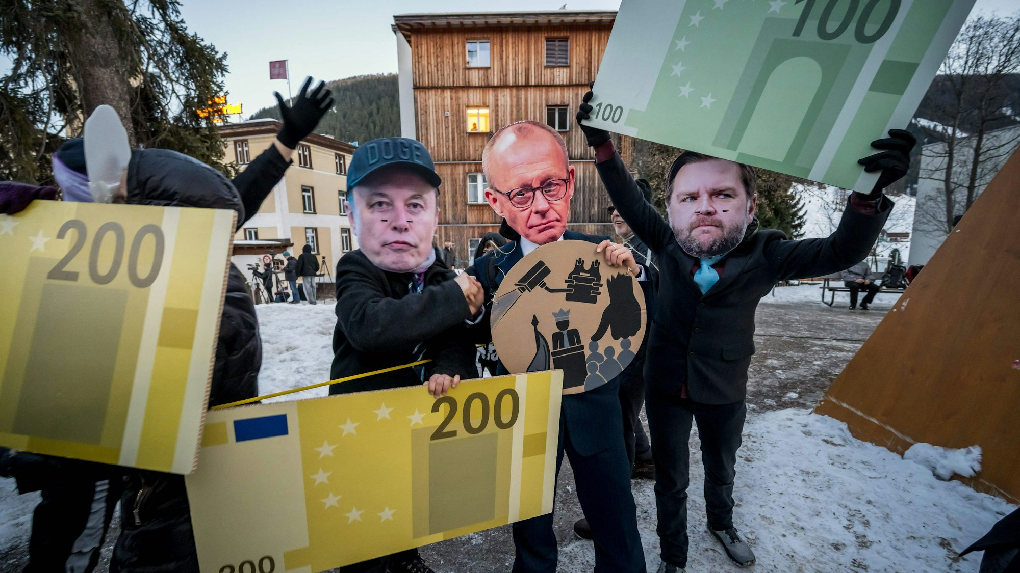 Demonstrierende mit Masken von Tesla-Chef Elon Musk, Bundeskanzler Friedrich Merz und US-Vizepräsident JD Vance halten Papp-Eurobanknoten während einer Protestaktion gegen das Weltwirtschaftsforum (WEF) am Vorabend der WEF-Jahrestagung am 18. Januar 2026 in Davos.