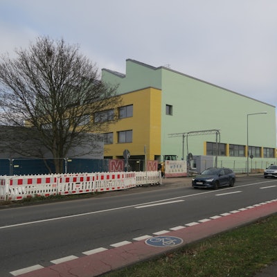 An einer großen Kreuzung steht ein grün-gelbes Schulgebäude.