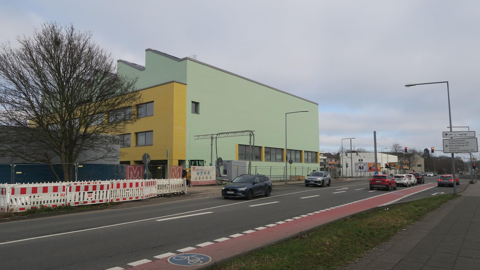 An einer großen Kreuzung steht ein grün-gelbes Schulgebäude.