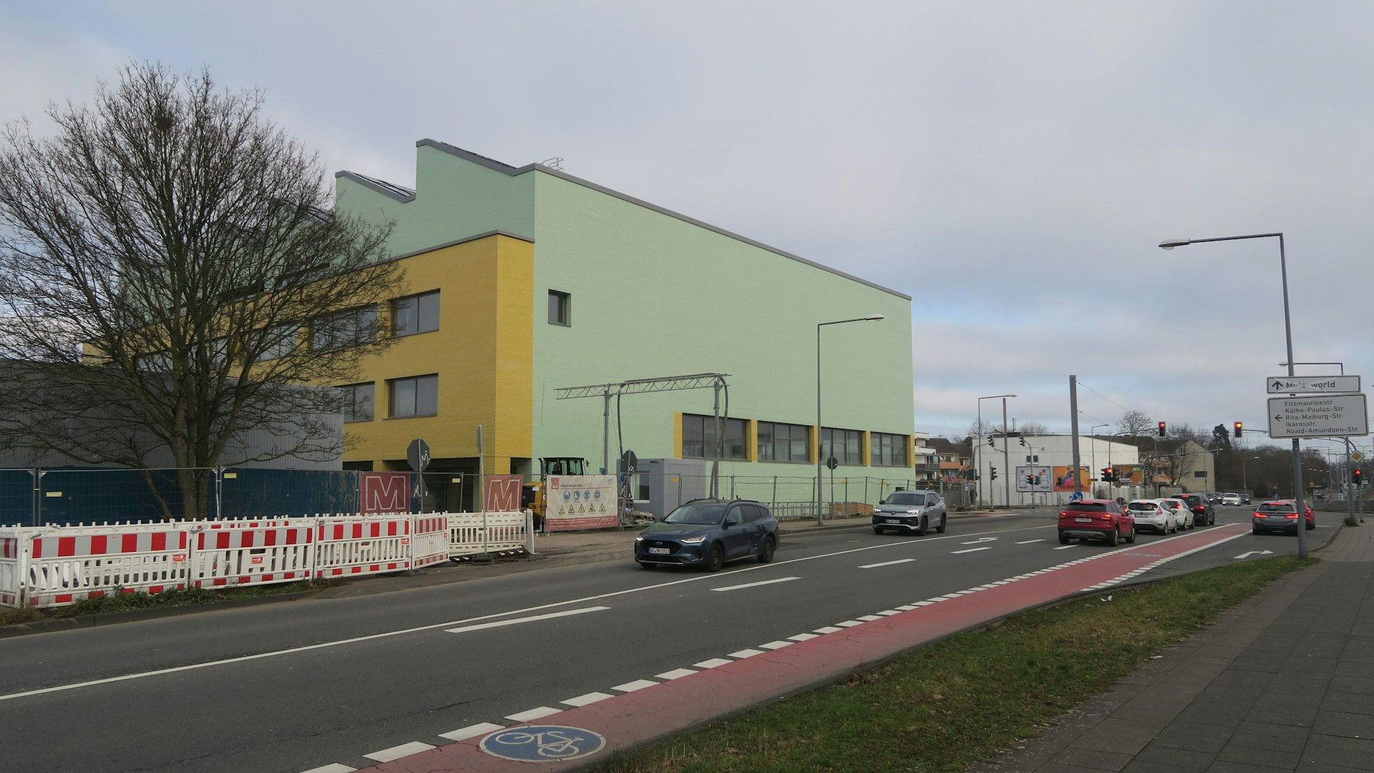 An einer großen Kreuzung steht ein grün-gelbes Schulgebäude.