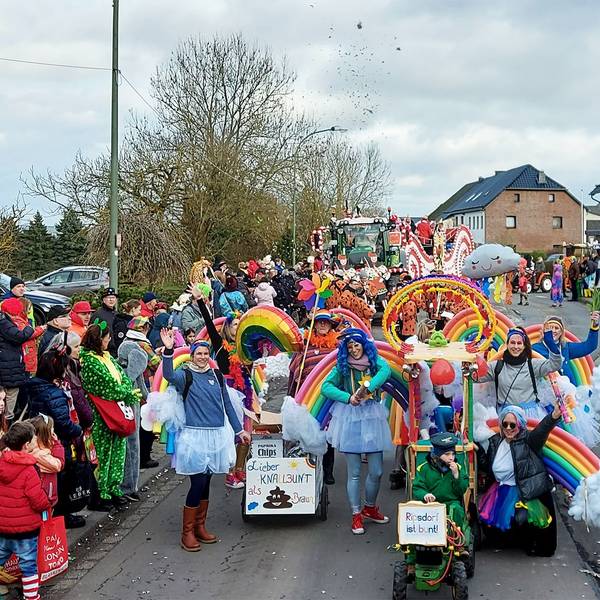 Eine als Regenbögen und Wolken kostümierte Gruppe läuft im Ripsdorfer Zug mit und jubelt den Jecken am Straßenrand zu.