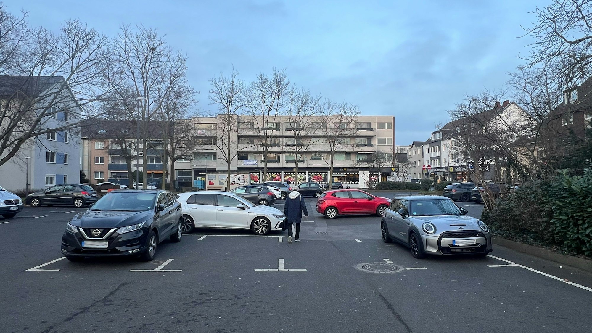Auf einem Parkplatz sind verstreut Autos abgestellt.