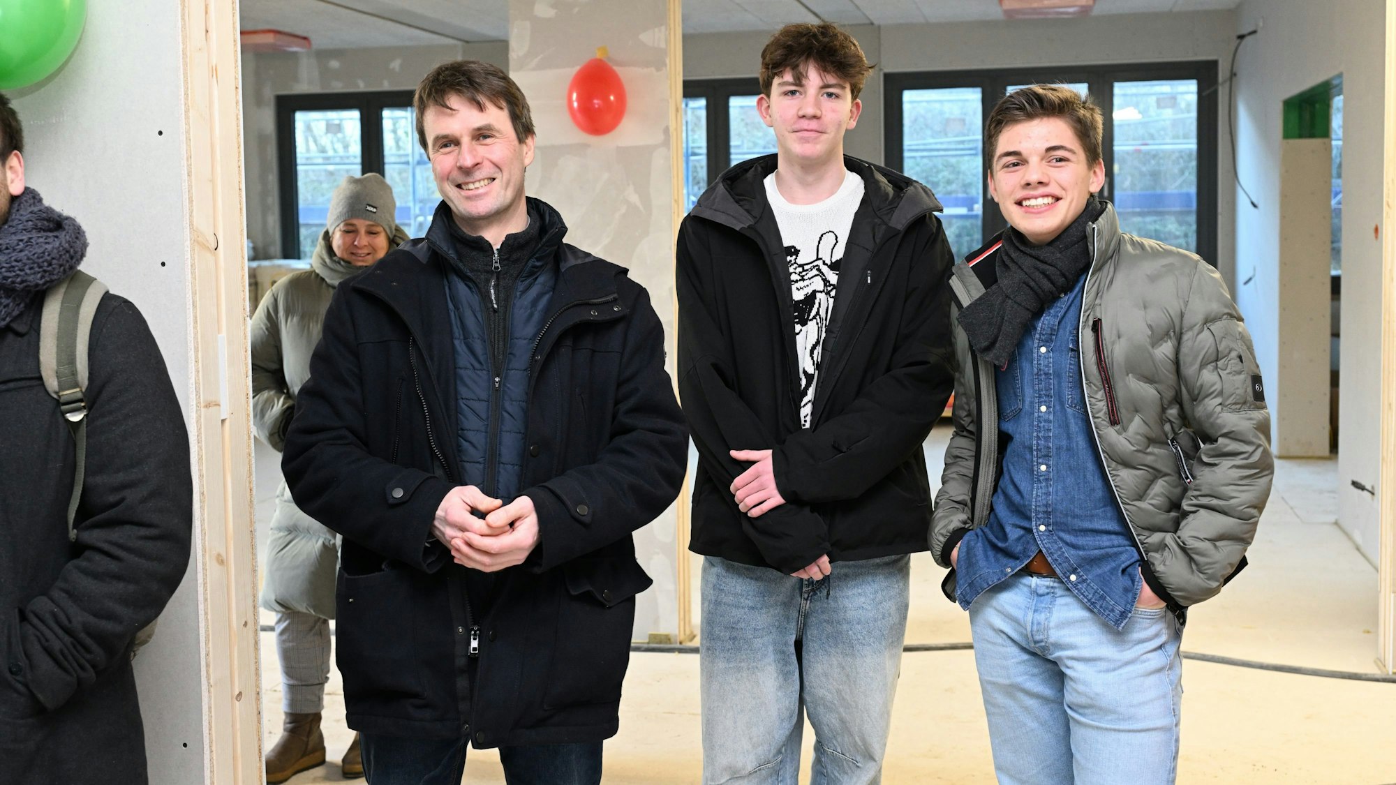 Die drei stehen nebeneinander un lächeln.