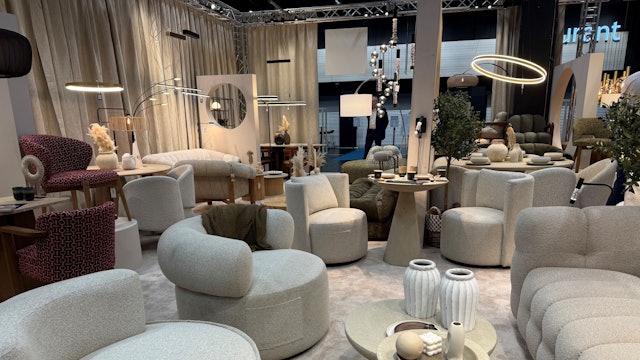 Helle Sofa mit passenden Hockern stehen in einem Ausstellungsraum.