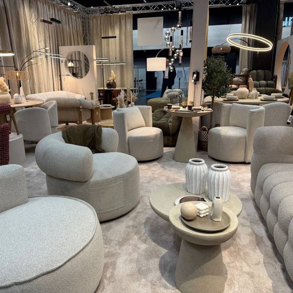 Helle Sofa mit passenden Hockern stehen in einem Ausstellungsraum.