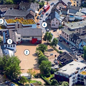 Eine Ansicht der von der Sonne beschienenen Ortsmitte von Hoffnungsthal aus der Vogelperspektive mit Schule, Schulhof, Freibad-Parkplatz und Hauptstraße.