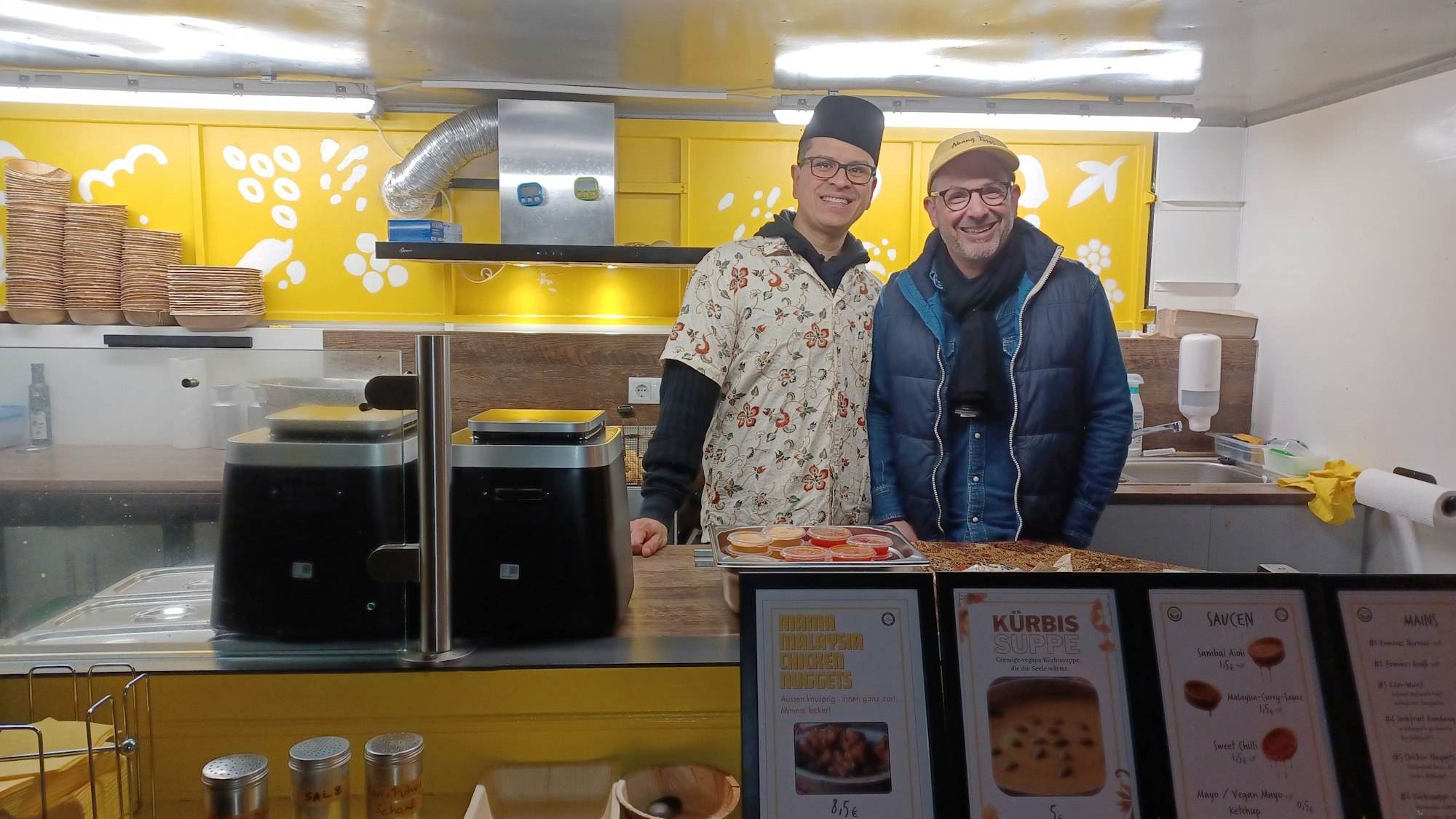 Zwei Männer stehen hinter der Verkaufstheke eines Imbisses.