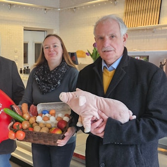 Zu sehen sind drei Männer und einer Frau, die Produkte eines Hofladens halten.