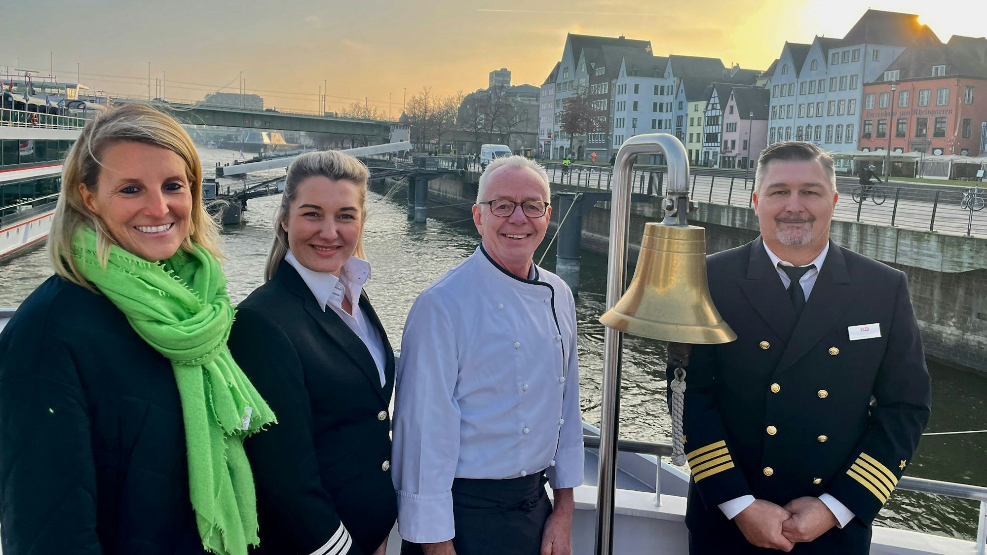 Zwei Frauen und zwei Männer stehen im Heck eines Schiffes vor dem Altstadt-Panorama Kölns.