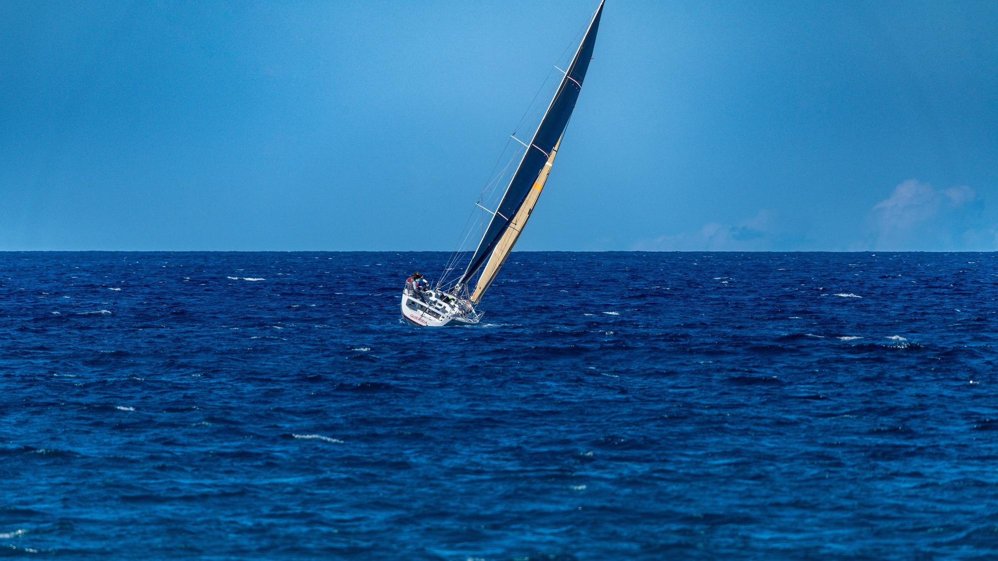 Eine Segelyacht lehnt sich bei klarem Himmel auf offener See in den Wind.