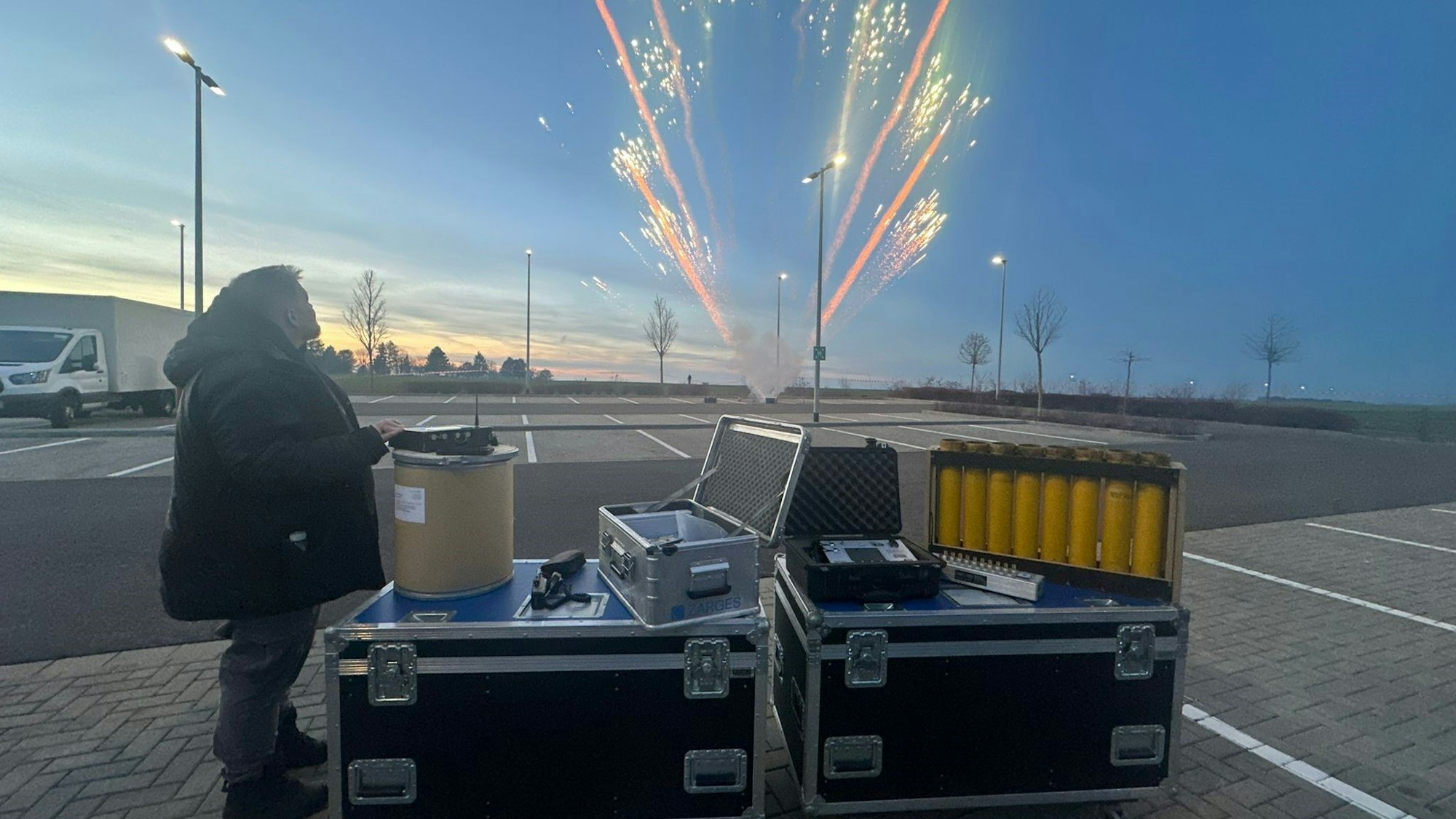 Das Bild zeigt einen Pyro-Techniker, der einen Feuerwerkskörper gezündet hat.