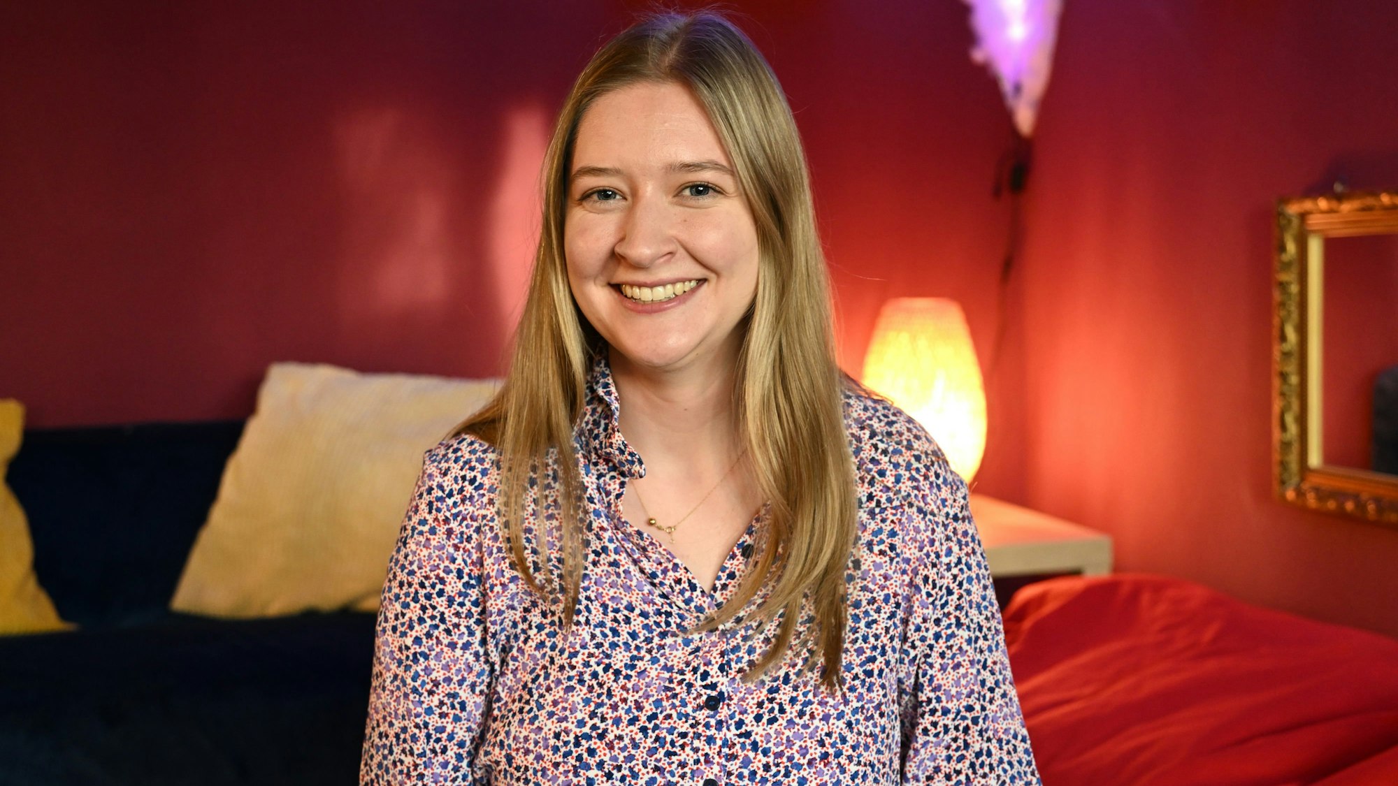 Eine junge Frau mit langen blonden Haaren lächelt in die Kamera.