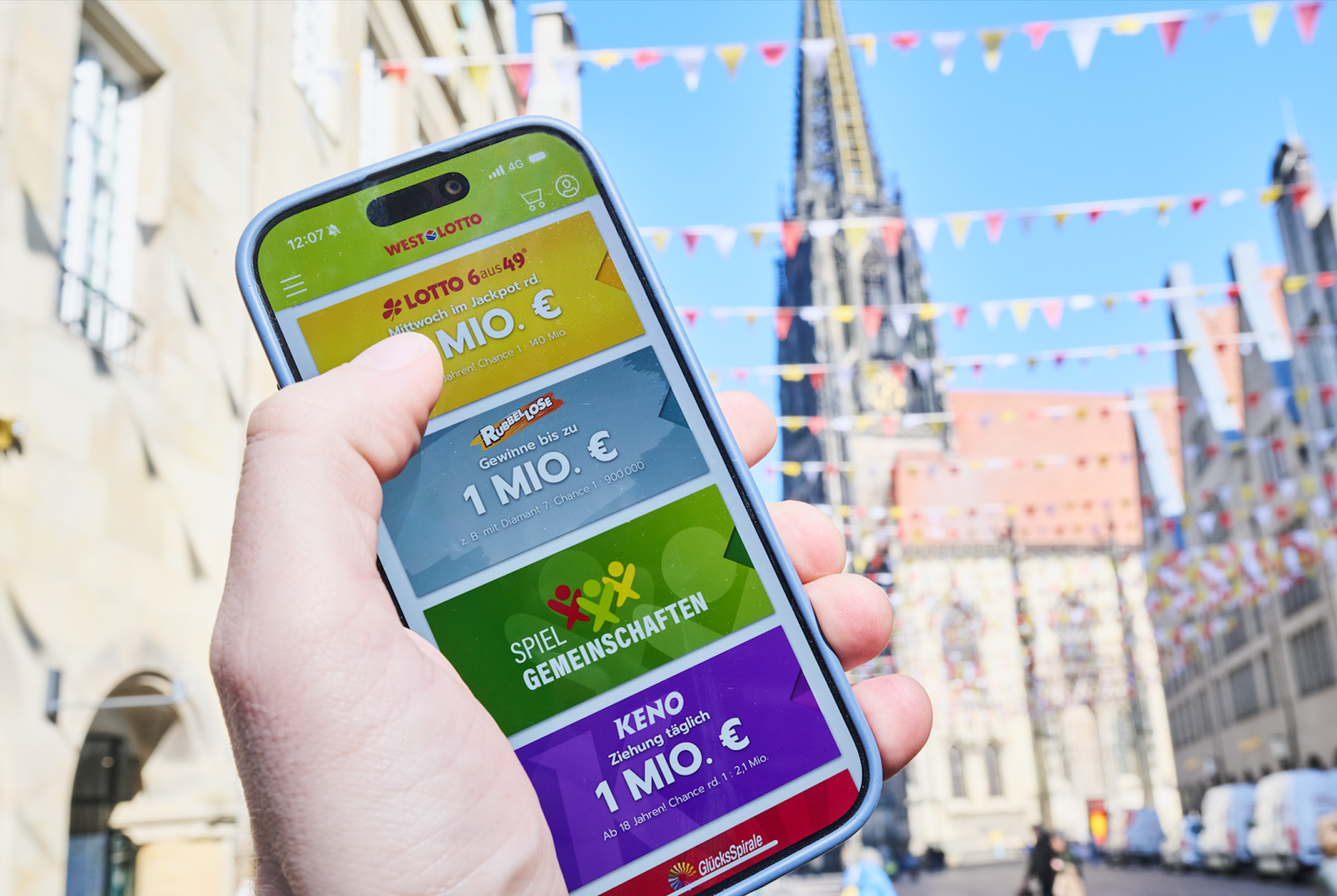 Das Bild zeigt eine Hand mit einem Handy. Das Display des Handys zeigt die WestLotto App.