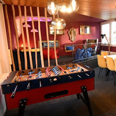 Ein Raum mit roten und orangen Wänden, einem Tischkicker und Spiegeln an den Wänden.